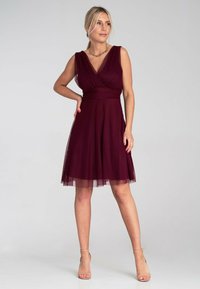 Burgunder Cocktailkleid mit tailliertem Oberteil, V-Ausschnitt, kurzen Ärmeln und einem schwingenden Rock aus weichem, durchscheinendem Stoff, der mit einem Tüllüberzug versehen ist.
