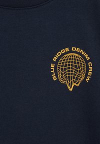 Jūrinės mėlynos spalvos apvalios kaklo megztinis su lygiu paviršiumi. Puošiamas geltonos spalvos žemėlapiu ir užrašu "BLUE RIDGE DENIM CREW."