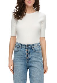 Witte geribbelde top met korte mouwen, gecombineerd met lichtblauwe high-waisted spijkerbroek met knoopsluiting en vijf zakken.