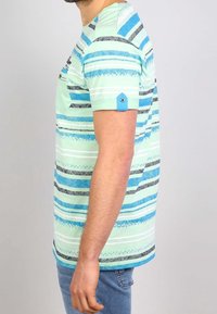 Camiseta de manga corta a rayas en azul claro y verde, con patrones de rayas negras y azul oscuro, con un bolsillo y un acento azul en la manga.