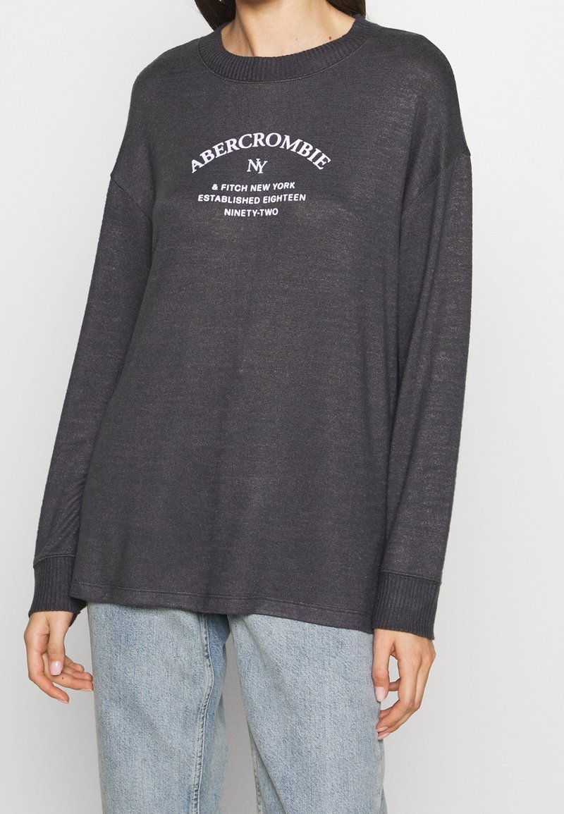 Sweatshirt oversize gris foncé avec un col rond côtelé, arborant le logo en texte blanc "Abercrombie & Fitch New York" sur la poitrine.