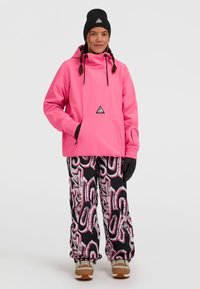 Roze gewatteerde jas met een zak aan de voorkant en zwarte accenten, gecombineerd met zwart-roze gestreepte sneeuwbroeken en beige laarzen. Zwarte gebreide beanie.