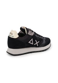 Sneaker nero e grigio realizzato in materiali scamosciati e in pelle. Presenta dettagli geometrici, un collare imbottito e una suola leggera grigia.