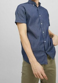 Košile s krátkými rukávy na zapínání na knoflíky z tmavě modrého denimu s klasickým límečkem, bílými knoflíky a volným střihem.