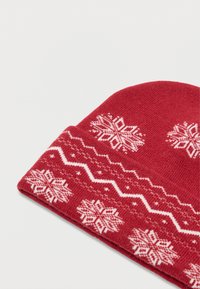 Gorro de inverno tricotado em vermelho com desenhos de flocos de neve brancos e um padrão em zig-zag na parte inferior, com uma textura suave e borda dobrada.