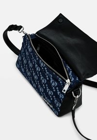 Borsa a mano in tessuto a motivi blu con patta e tracolla in pelle nera. Dotata di chiusura con zip e hardware argento, con un ampio interno.