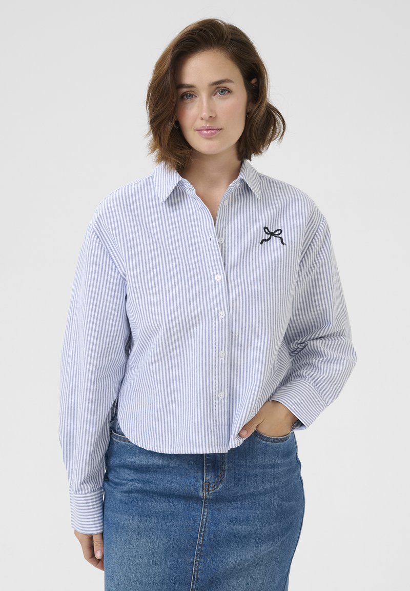 Koszula button-up w niebiesko-białe paski, wykonana z bawełny, z długimi rękawami, szpiczastym kołnierzykiem oraz małym czarnym haftem w kształcie kokardy na piersi.