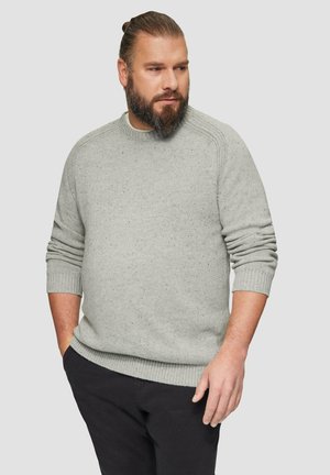 Pull en maille gris clair avec une finition texturée, des poignets et un ourlet côtelés, un col rond et un motif subtil moucheté, associé à un pantalon sombre.