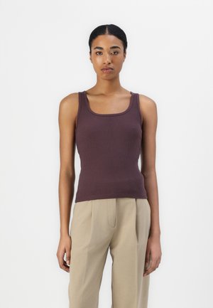 Débardeur marron à côtes avec un décolleté carré, associé à un pantalon beige clair. Le tissu semble lisse avec une coupe ajustée.