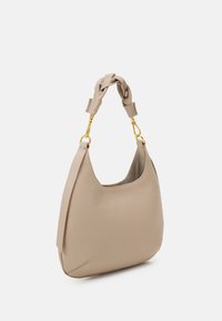 Beige nahkakäsilaukku, jossa on solmittu kahva, kultaiset yksityiskohdat ja pehmeä, teksturoitu pinta; pyöreä muoto ja avotoppi.