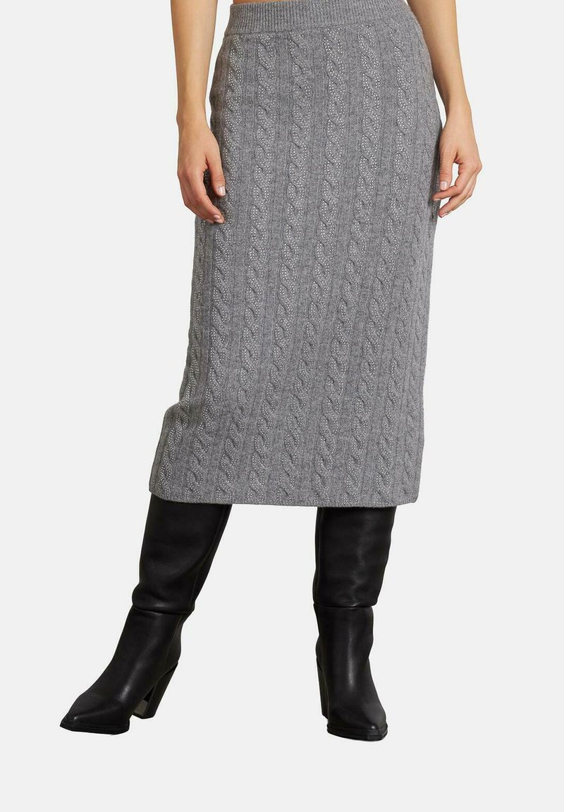 Grijze kabelgebreide midi-rok met een ribbels waistband, gecombineerd met zwarte kniehoge laarzen. De stof heeft een textuur en een gezellige uitstraling.