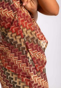 Vestido multicolorido con un patrón texturizado que presenta formas entrelazadas en rojo, dorado y marrón, con un detalle de abertura lateral.