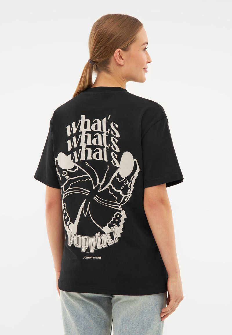 Černé bavlněné tričko s velkým bílým potiskem na zádech s textem "co se děje?!" a designem motýla. Krátké rukávy.