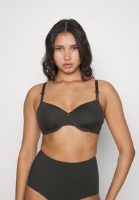 Black semi-padded bra with adjustable straps, smooth texture, and a clasp closure. Paired with high-waisted black underwear.