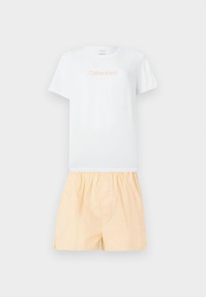 Λευκό κοντομάνικο t-shirt Calvin Klein με λογότυπο σε ανοιχτό πορτοκαλί, συνδυασμένο με άνετο σορτς σε ανοιχτό ροδακινί χρώμα με ελαστική μέση.