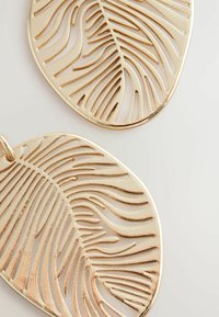 Goldfarbene Ohrringe mit einem Blätterdesign, das Ausstanzungen, verlängerte Formen und eine glatte glänzende Oberfläche aufweist.