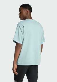 Σαπούνι βαμβακερό μπλε ανοιχτό μπλουζάκι με κοντό μανίκι, χαλαρή εφαρμογή και κυκλή λαιμόκοψη, εμφανίζεται από πίσω σε ουδέτερο φόντο.