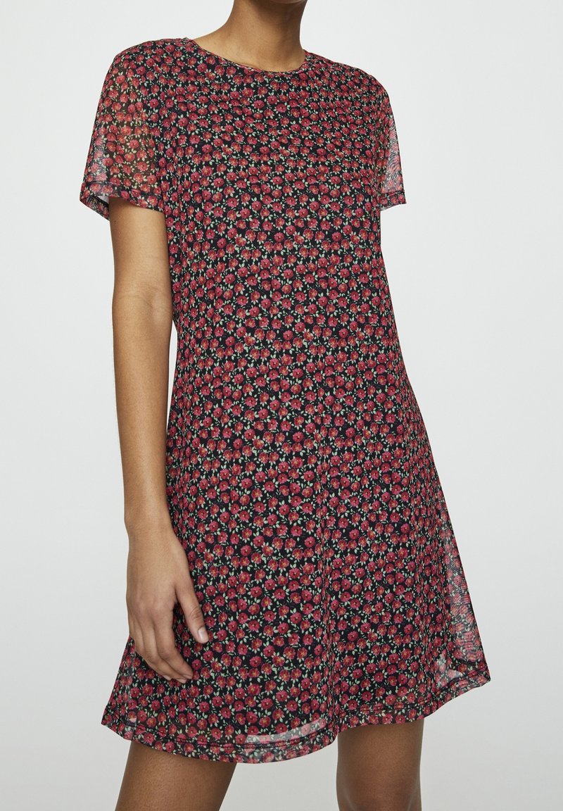 Robe à manches courtes, longueur genou en tissu noir avec un motif floral rouge. Texture légère et translucide, encolure ronde, silhouette fluide.