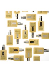 Clinique fuktighetskrem i rektangulære gule flasker med sølvspraylokker, med etiketter i svart og hvit tekst, arrangert tilfeldig.