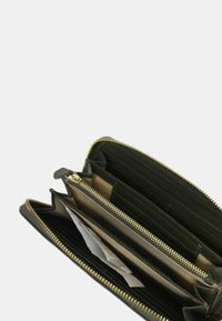 Portafoglio in pelle nera con zip dorata, dotato di molteplici scomparti per carte e banconote, e una superficie liscia all'esterno.