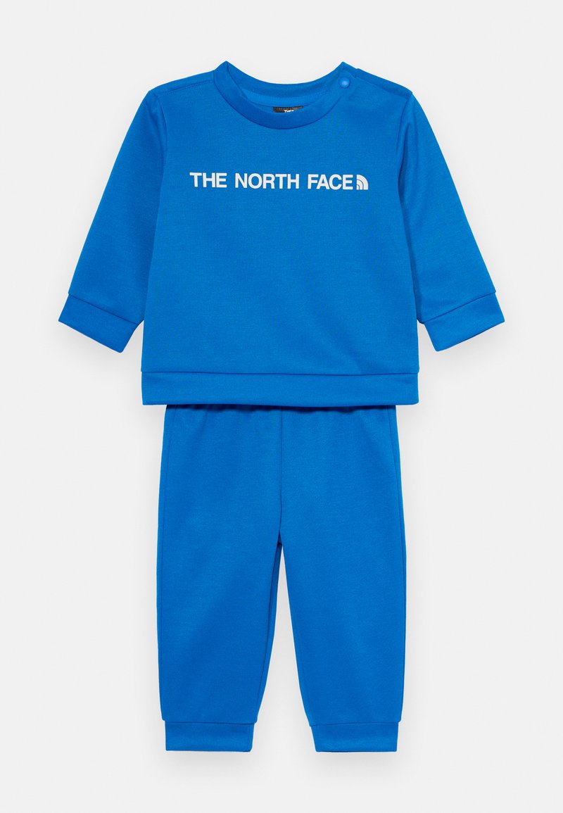 Μπλε σετ δύο τεμαχίων που περιλαμβάνει μια φούτερ μακρυμάνικη με λαιμόκοψη και το λογότυπ�ο "THE NORTH FACE", σε συνδυασμό με αντίστοιχες tapered παντελόνες.