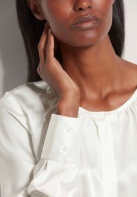 Witte satijnen blouse met een geplooide halslijn en knoopmanchetten. Gladde textuur, met een ontspannen pasvorm en zachte val.