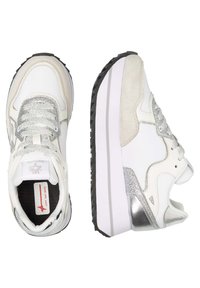 Sneakers bianchi con accenti argento, camoscio testurizzato e pelle liscia, con una suola spessa bianca e lacci riflettenti. Sottopiede in gomma nera.