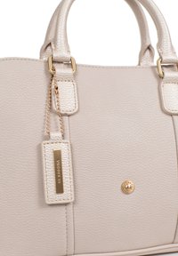 Borsa in pelle sintetica beige con hardware dorato, superficie testurizzata e un'etichetta attaccata da una catena. Presenta un accento centrale dorato.