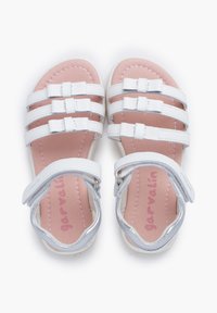 Białe sandały na paski z pięcioma paskami, srebrnymi akcentami, różową wkładką i zapięciem na rzep wokół kostki. Gładka faktura z przeszyciami.