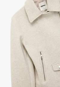 Giacca in misto lana grigio chiaro con colletto, tasca frontale con zip argentata e una finitura leggermente strutturata.