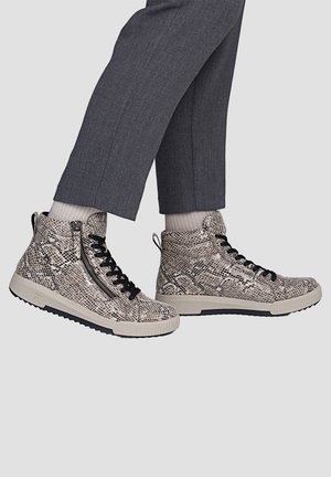 Feet wearing high-top sneakers with snakeskin pattern, black laces, and side zipper, paired with gray pants and light-colored socks.