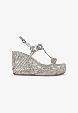 Sandalia cuña plateada con textura trenzada, diseño de tira en T, embellecida con strass y correa adjustable al tobillo.