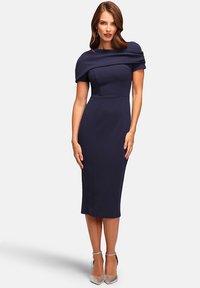 Marineblaue, figurbetonte Kleider mit einem drapierten, schulterfreien Design, knielangem Schnitt und strukturiertem Stoff. Kombiniert mit silbernen High Heels.