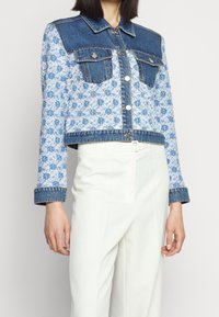 Jeansjacka med blå mönstrad tyg, kortad design, två bröstfickor och knappstängning. Ärmarna har denimmanschetter.