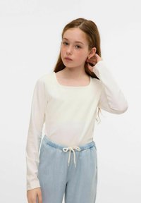 Top bianco a maniche lunghe con scollatura quadrata, abbinato a pantaloni azzurri con cordoncino. Tessuto morbido e vestibilità rilassata.