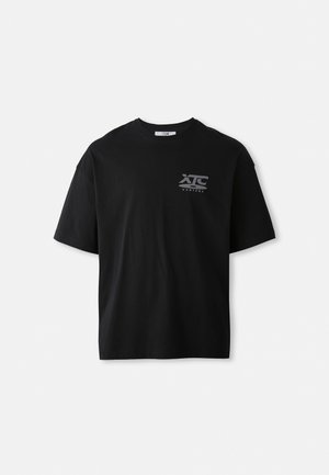 Black short-sleeve cotton t-shirt featuring a crew neck and a white logo "XTC VERTERE" on the left chest area. Smooth texture.