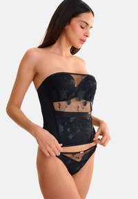 Zwarte korsettop met bloemenborduursel, doorschijnende gaaspanelen en een gestructureerde vorm. Bijpassende zwarte bikini met soortgelijke gaasaccenten.