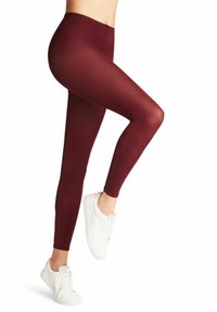 Leggings elasticizzati color bordeaux con vita alta, texture liscia e design aderente, abbinati a sneakers bianche per un look casual.