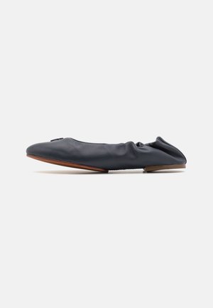 Ballerine en cuir noir souple avec bout arrondi, talon élastiqué et semelle fine marron, vue de côté sur fond blanc.
