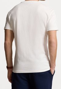 Men's short-sleeve t-shirt in cream cotton. Round neck, smooth texture, simple design, with a back view showcasing the fit.