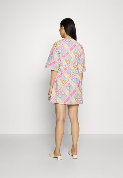 Vestido de manga curta com um padrão geométrico multicolorido sobre um fundo claro, com cintura marcada por um cinto e um design até ao joelho.
