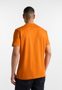 Oranžové bavlnené tričko s krátkymi rukávmi a klasickým okrúhlym výstrihom, s hladkou textúrou a rovnom strihom na spodnom okraji.