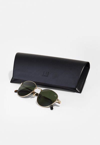 Lunettes de soleil rondes avec des verres verts et une monture en métal doré, accompagnées d'un étui en cuir noir embossé d'un logo.