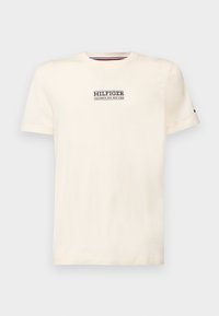 Krémové tričko s krátkým rukávem a kulatým výstřihem s textem "HILFIGER COLUMBUS AVE. NEW YORK" umístěným uprostřed na hrudi a malým logem na levém rukávu.