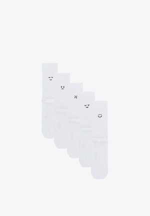 Vijf witte sokken naast elkaar gerangschikt, elk met een ander zwart emoji-gezicht dat verschillende emoties toont op het bovenste gedeelte.