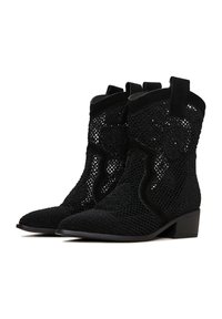 Botas de cowboy negras con diseño de encaje tejido, punta afilada y tacón bajo. Los acentos de ante realzan la textura y el interés visual.