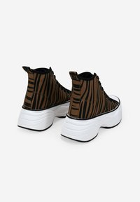 Zapatillas altas a rayas marrones y negras con una suela blanca gruesa, que cuentan con un acabado texturizado y una pestaña en la parte trasera.