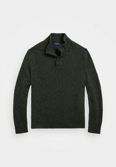 Maglione a maglia verde scuro con colletto alto, pattina con tre bottoni, polsini e orlo a coste, con pezzetti di colore più chiaro distribuiti su tutta la superficie.