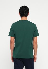 Mørkegrøn kortærmet t-shirt, lavet af bomuld, har rund hals og et enkelt design uden synlige mønstre eller detaljer.
