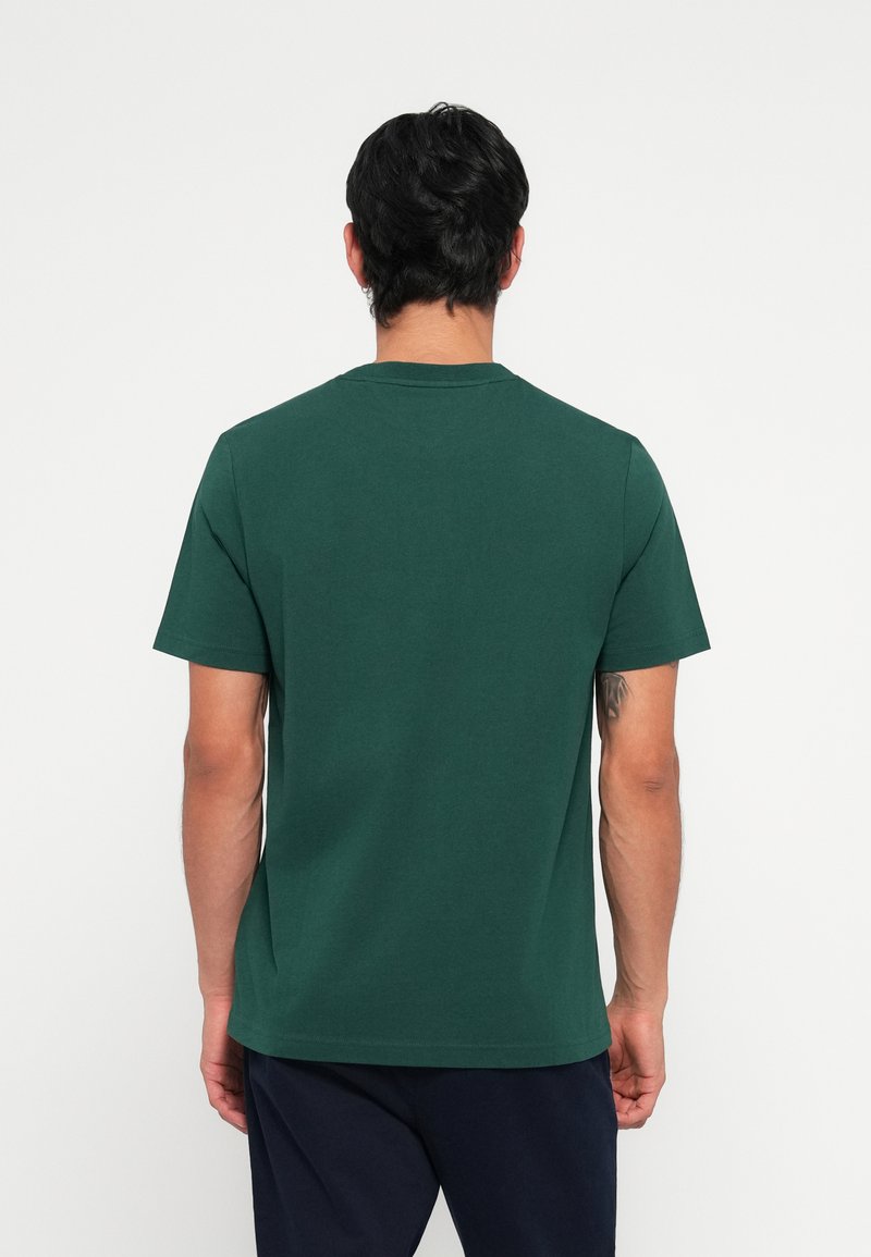 Camiseta de manga corta verde oscuro, hecha de algodón, con cuello redondo y un diseño liso, sin patrones ni acentos visibles.